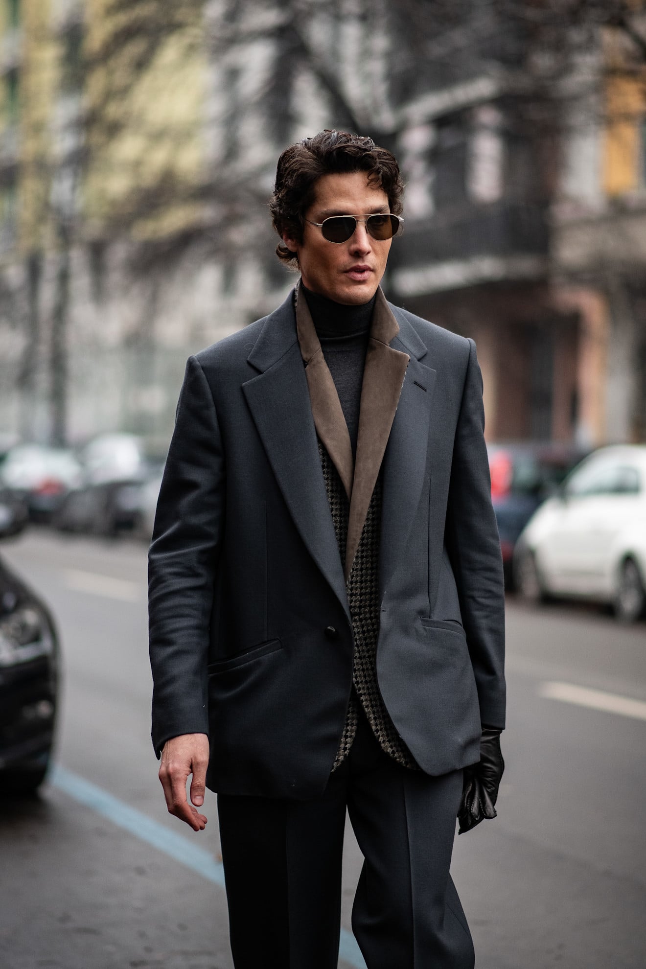 A man with a grey oversized suit with a brown undercoat layer and black knitwear baselayer