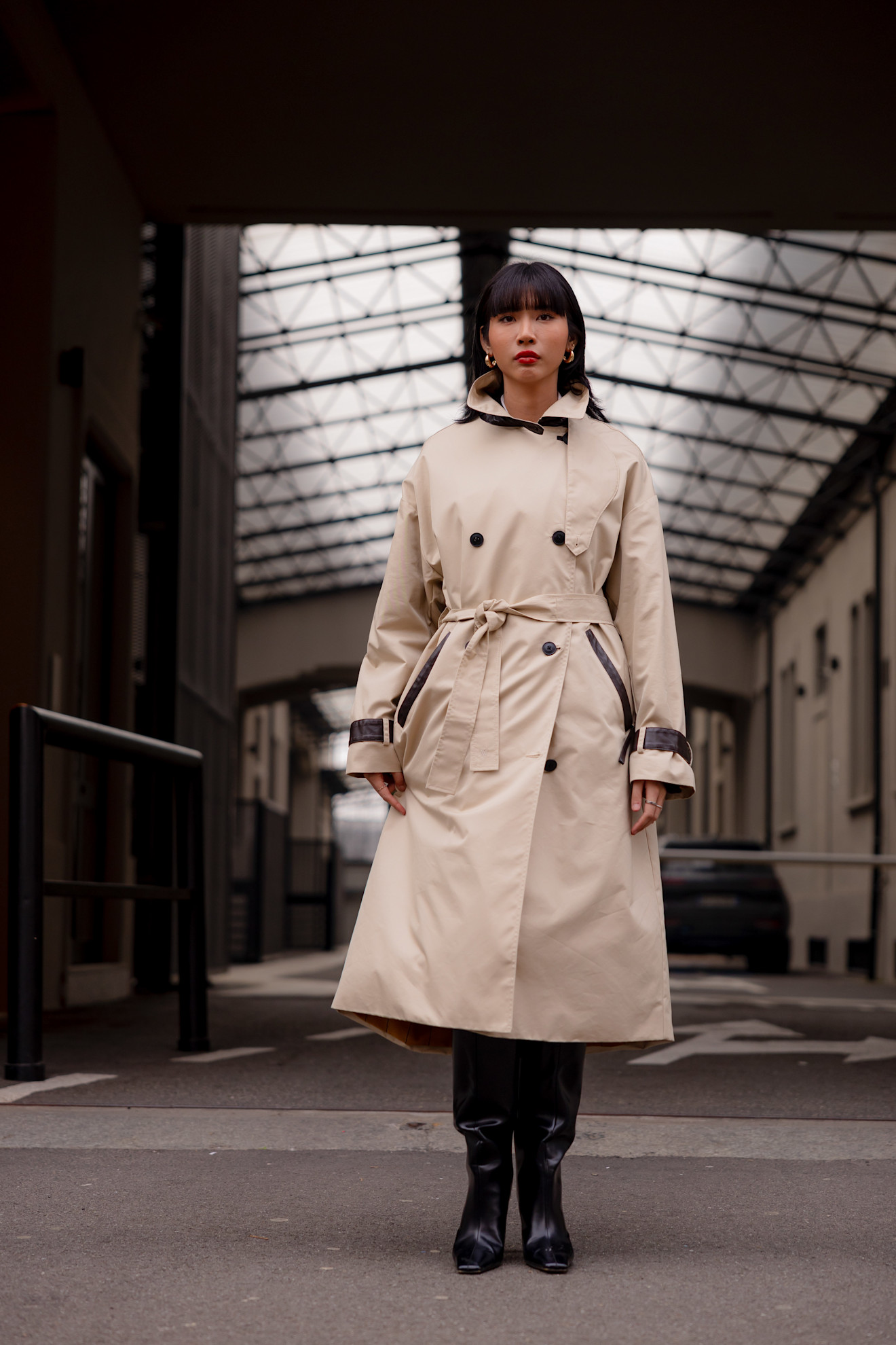 A woman wearing a classic lght camel coloured double-breasted trench made out of a technical nylon fabric